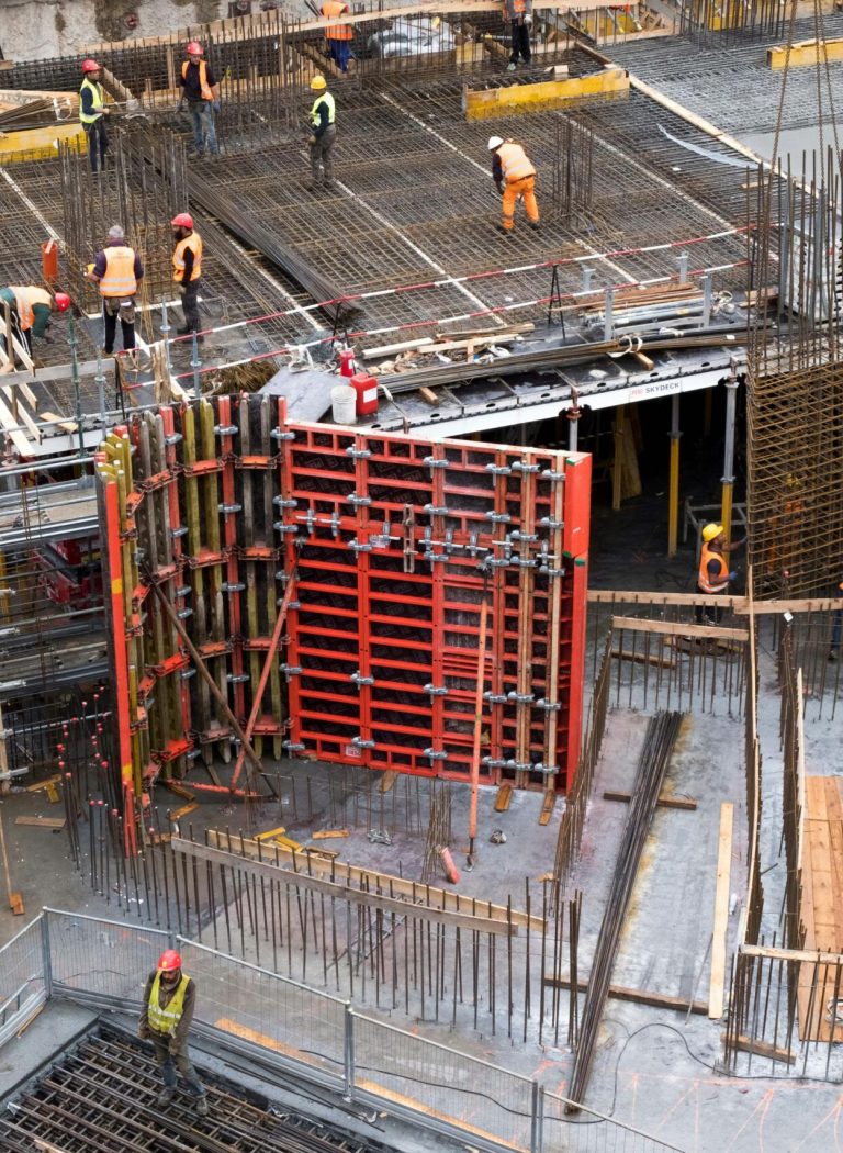 Industrial construction site with workers in high visibility clothing at a steel framework structure.
